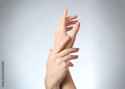 Hands of young woman on light background