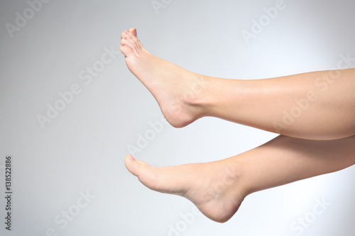 Legs of young woman on light background