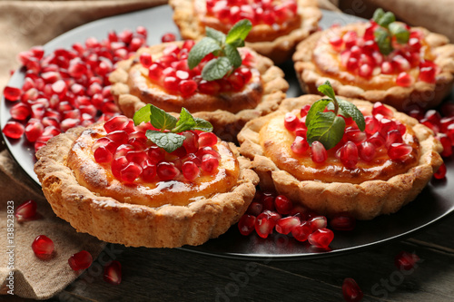 Tasty tarts with fresh seeds of pomegranates served on plate, closeup