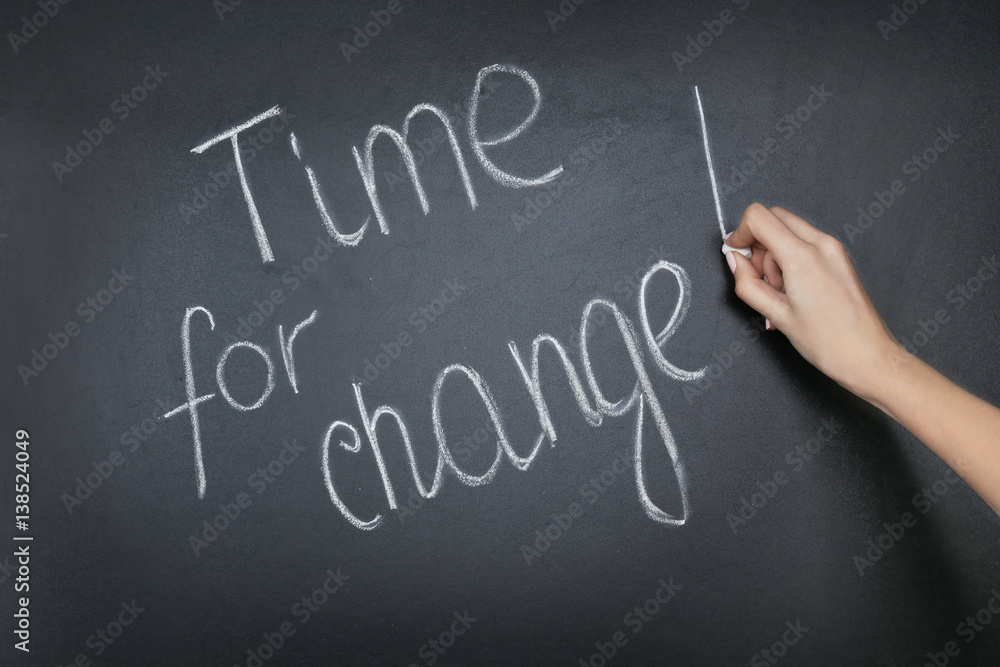 Female hand writing phrase TIME FOR CHANGE on blackboard Female hand writing phrase TIME FOR CHANGE on blackboard