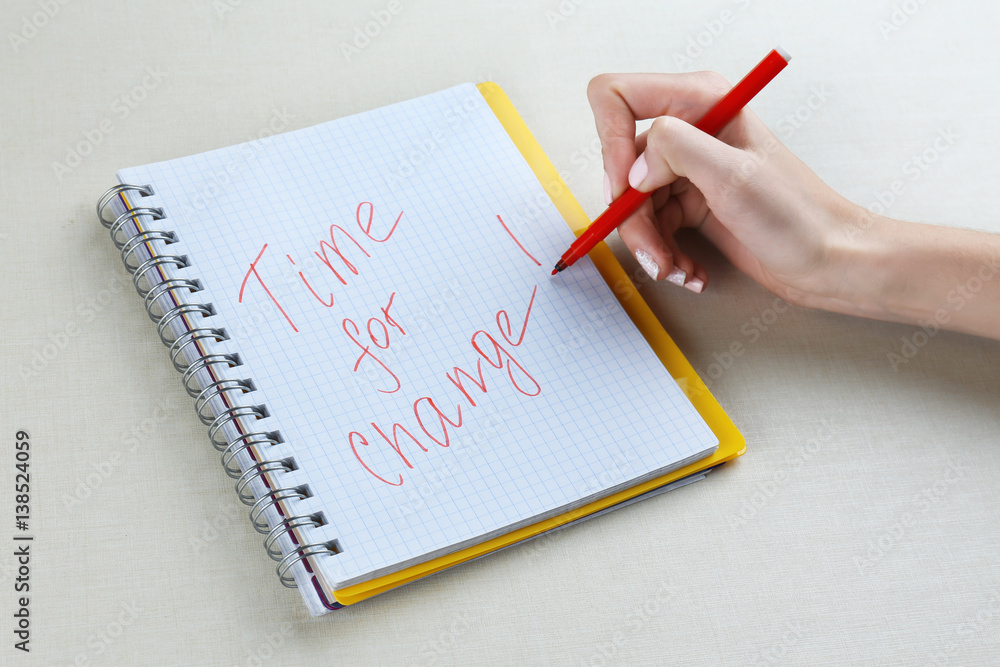 Female hand writing phrase TIME FOR CHANGE in notebook Female hand writing phrase TIME FOR CHANGE in notebook