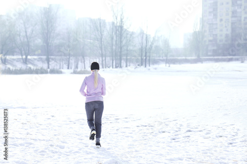 Sportive young woman running in winter park
