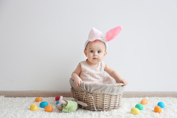 Cute funny baby with bunny ears and colorful Easter eggs at home