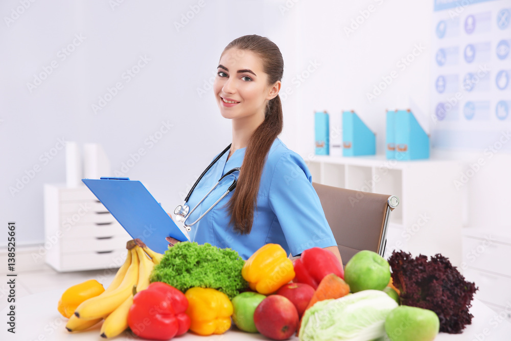 Young female nutritionist with vegetables and fruits in her office Young female nutritionist with vegetables and fruits in her office