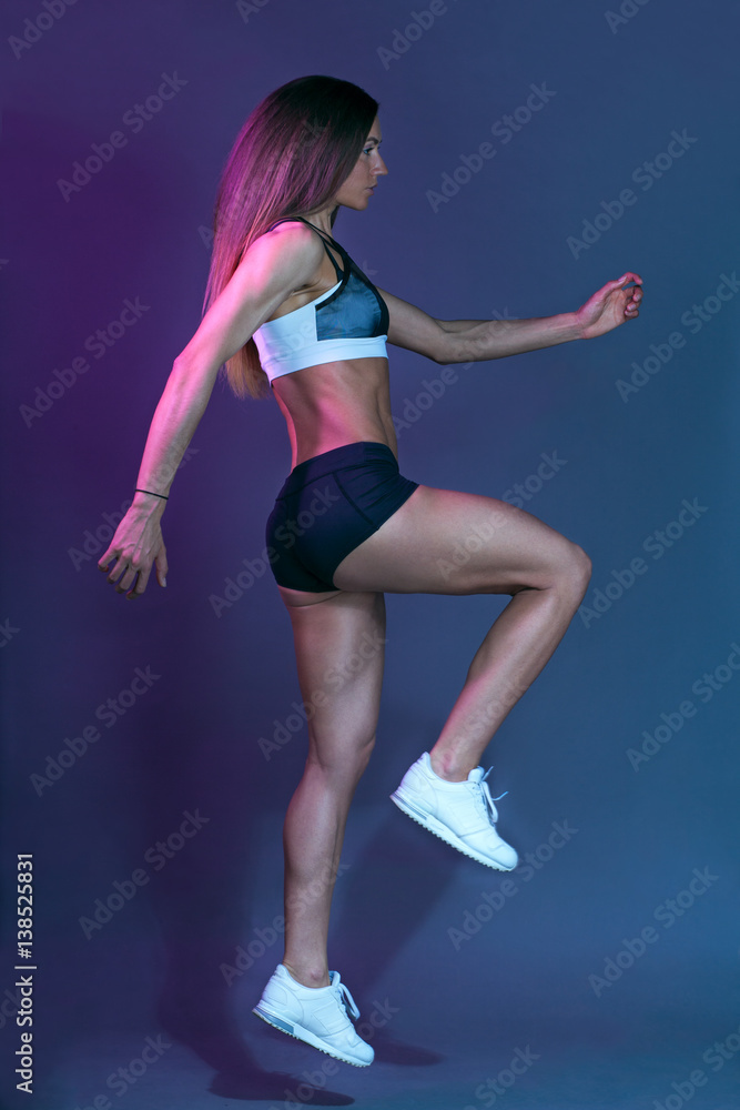 athletic sportswoman in sportswear jumping isolated on motley background