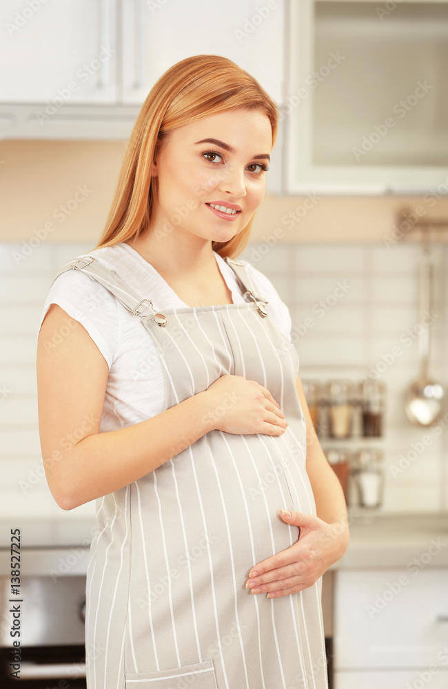 Young beautiful pregnant woman touching belly at kitchen Young beautiful pregnant woman touching belly at kitchen