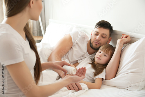 Young woman with pills for her ill daughter and husband at home