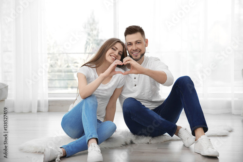 Happy young couple sitting on floor at home