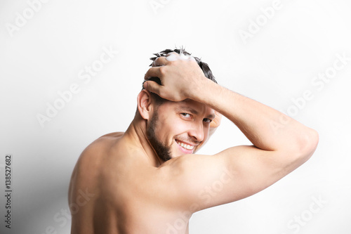 Young handsome man washing hair on white background