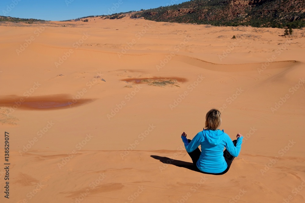 Woman meditating  in desert.  Coral Pink Sand Dunes State Park. Cedar City. Kanab. Utah. United States.