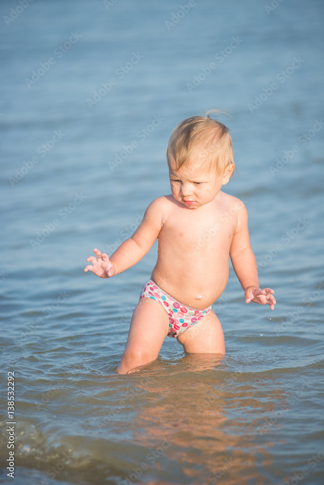 Baby playing on the sandy beach and in sea water. Cute little kid with toys on sand tropical beach. Ocean coast. Baby playing on the sandy beach and in sea water. Cute little kid with toys on sand tropical beach. Ocean coast.