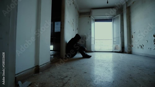 Hooded depressed young man in empty abandoned house