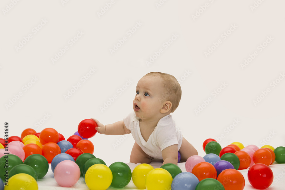 8 month baby boy playing with color balls. White background 8 month baby boy playing with color balls. White background