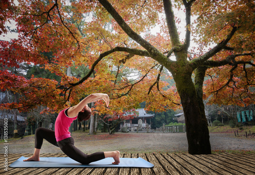 Sporty fit women practices yoga Anjaneyasana - low crescent lunge under maple tree in autumn season. photo