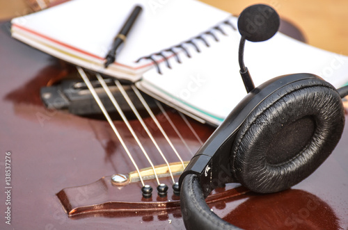 Music book, notepad pen headphone and acoustic guitar on old table