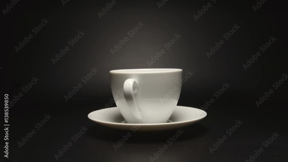 White coffee cup is rotating on black background (stop motion) White coffee cup is rotating on black background (stop motion)