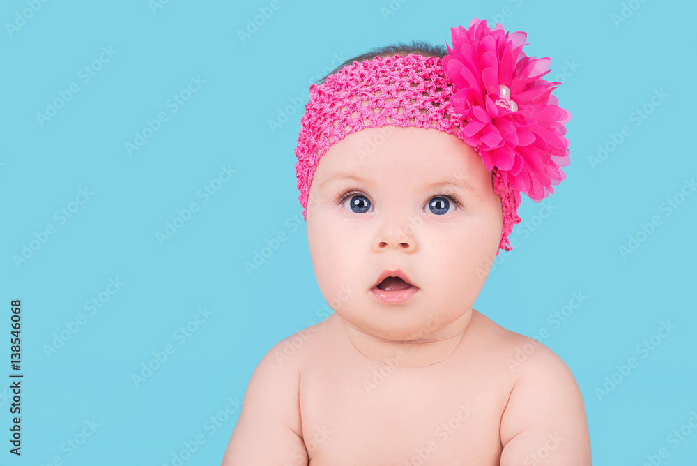 cute baby with pink bow flower on head, isolated on blue cute baby with pink bow flower on head, isolated on blue