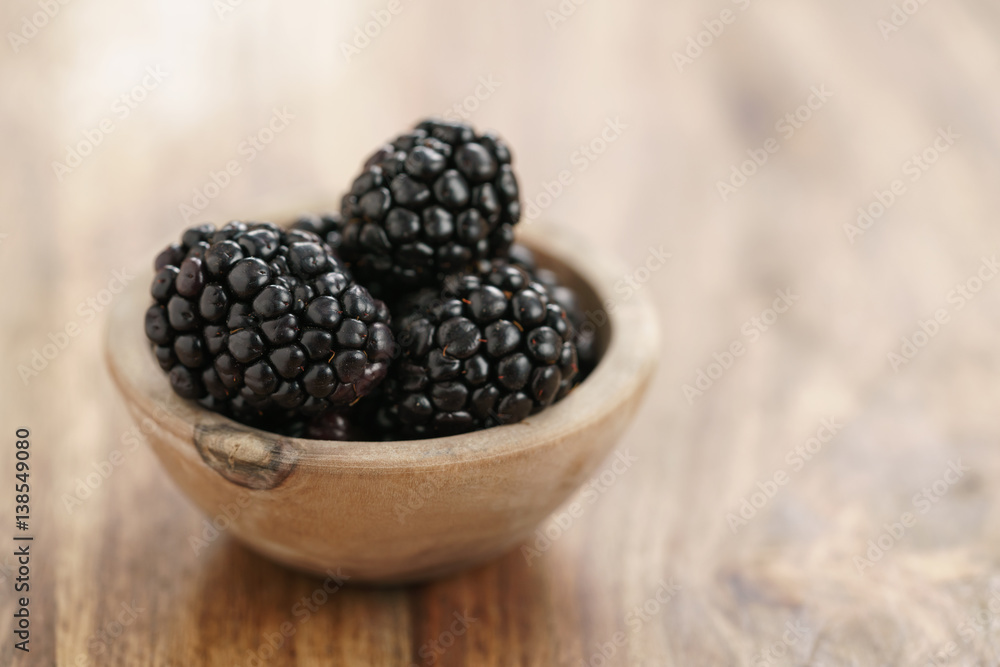 fresh blackberry in wooden bowl on table, with copy space fresh blackberry in wooden bowl on table, with copy space