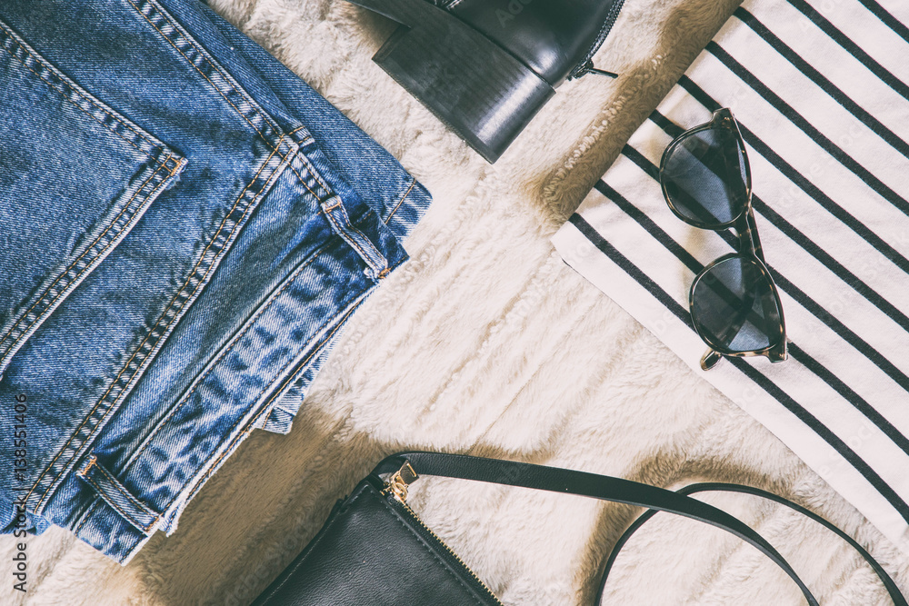 perfect spring outfit accessories. flat lay of a trendy fashion outfit, denim  jeans, striped shirt, black ankle boots and a small elegant black purse.  top view. Photos | Adobe Stock