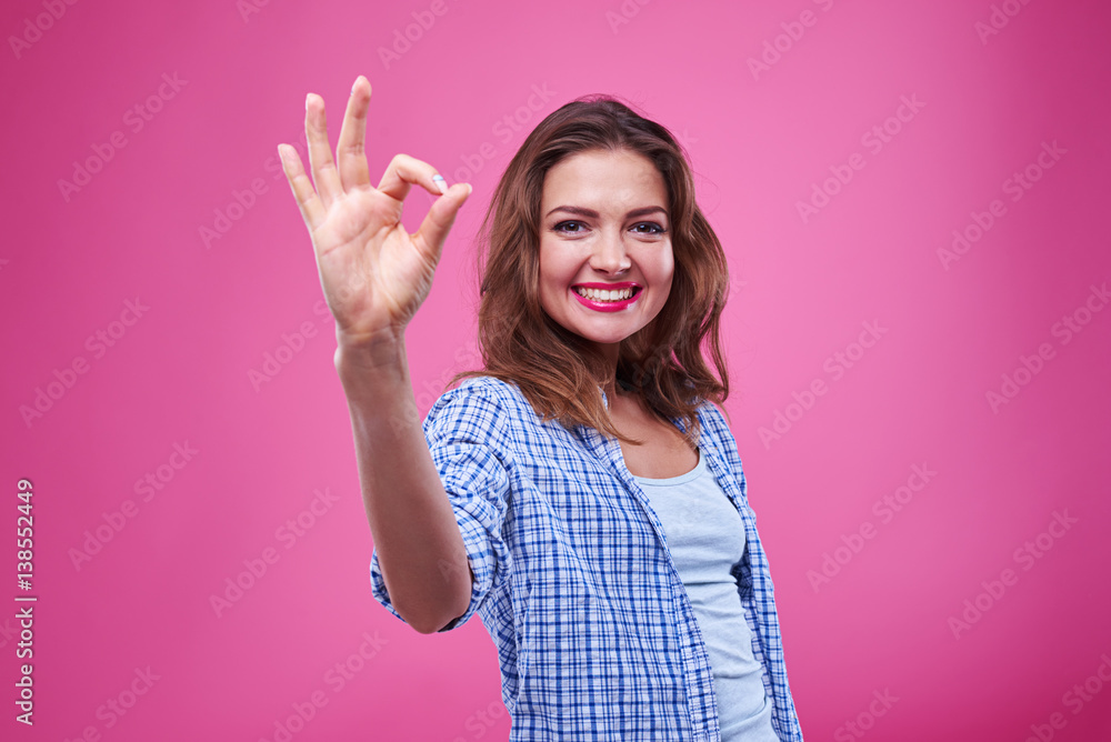 Charming girl showing ok gesture isolated over pink background Charming girl showing ok gesture isolated over pink background