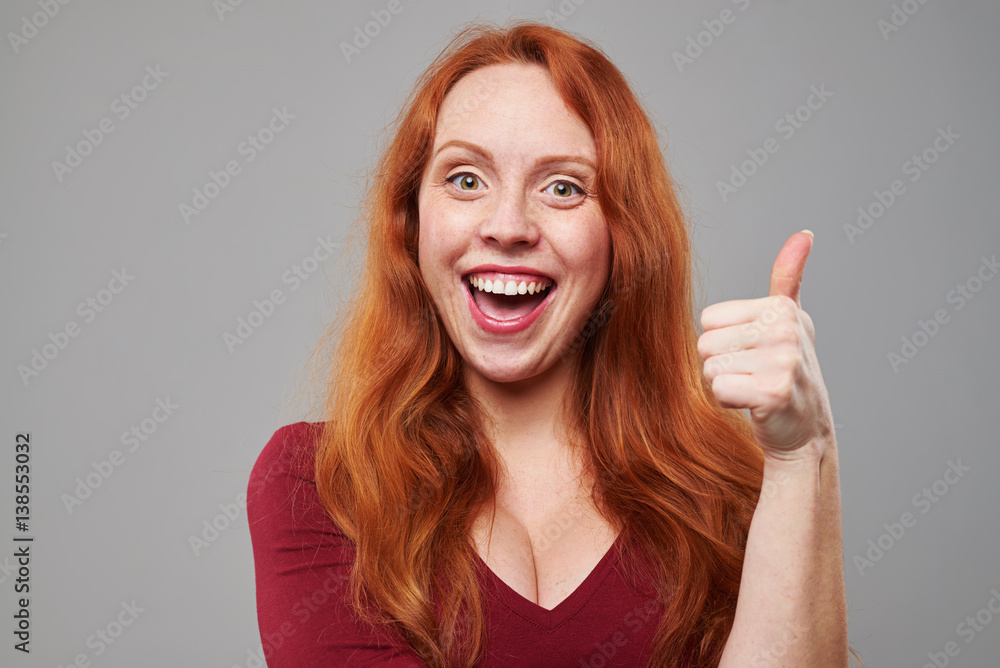 Cheerful woman with auburn hair holding ok gesture Cheerful woman with auburn hair holding ok gesture