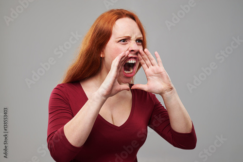 Angry redhead young woman loudly screaming