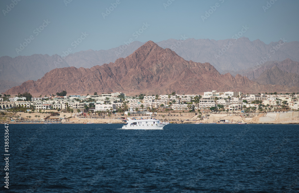 View at the shore of Sham El-Sheikh, white yacht and Sinai in summertime