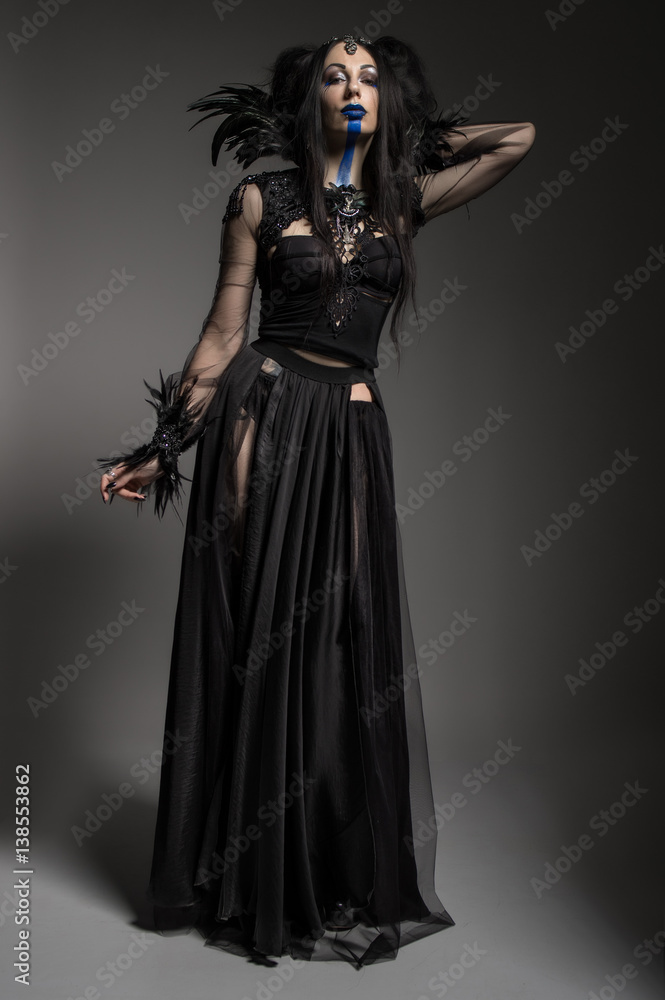 Young woman in black fantasy costume with feathers on dark background Young woman in black fantasy costume with feathers on dark background