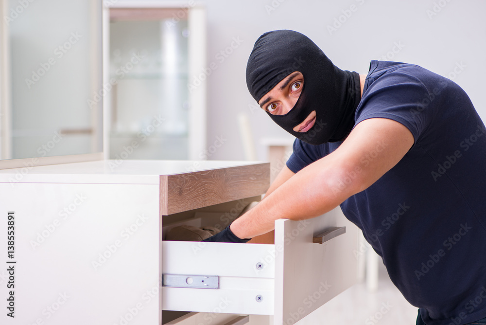 Robber wearing balaclava stealing valuable things Robber wearing balaclava stealing valuable things