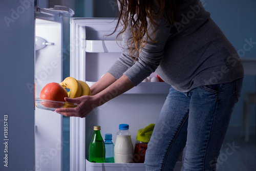Pregnant woman near fridge looking for food and snacks at night
