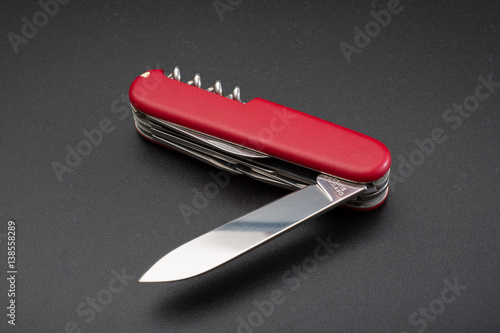 Fotografi Red multitool open knife on black background