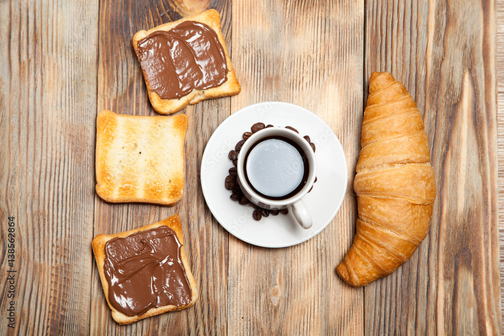 cup of coffee, croissant, toast and chocolate on wooden table cup of coffee, croissant, toast and chocolate on wooden table