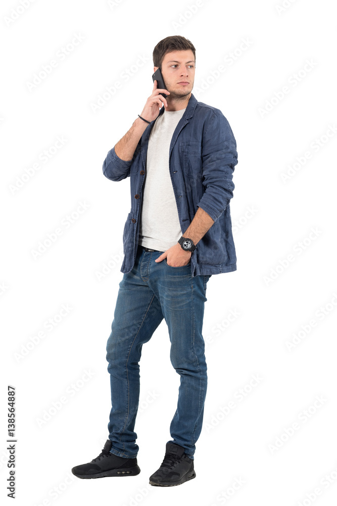 Modern stylish casual man talk on the mobile phone looking back over shoulder. Full body length portrait isolated over white background. Modern stylish casual man talk on the mobile phone looking back over shoulder. Full body length portrait isolated over white background.