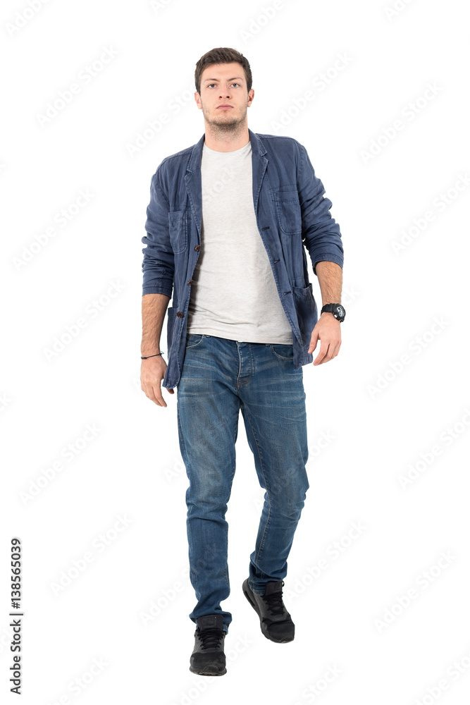 Young confident man in denim unbuttoned shirt and jeans walking towards camera. Full body length portrait isolated over white background. Young confident man in denim unbuttoned shirt and jeans walking towards camera. Full body length portrait isolated over white background.