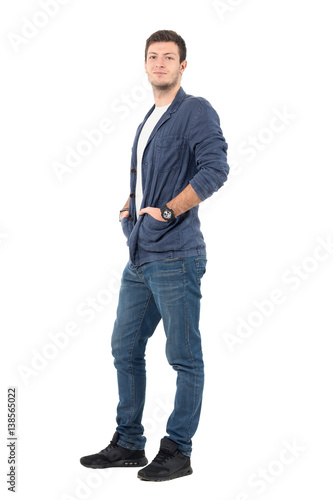 Smiling relaxed man in jeans and denim shirt with hands in pockets. Full body length portrait isolated over white background.