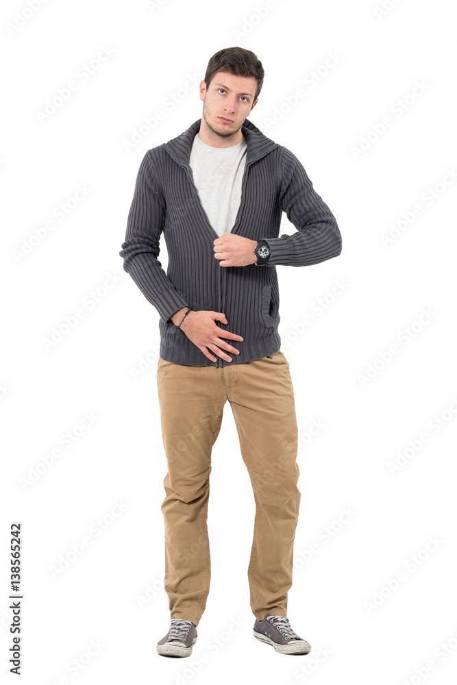 Casual man zipping jumper sweater looking at camera. Full body length portrait isolated over white background. Casual man zipping jumper sweater looking at camera. Full body length portrait isolated over white background.