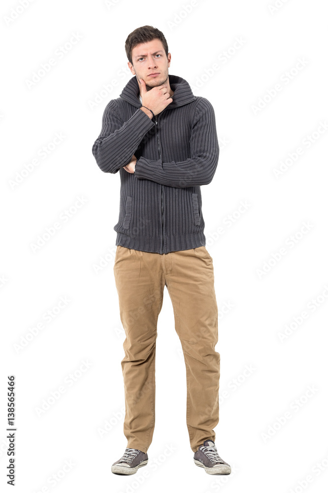Skeptical doubtful man with hand under chin looking at camera suspiciously. Full body length portrait isolated over white background. Skeptical doubtful man with hand under chin looking at camera suspiciously. Full body length portrait isolated over white background.