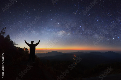 milky way galaxy and silhouette of a standing happy man on Doi inthanon Chiang mai, Thailand.