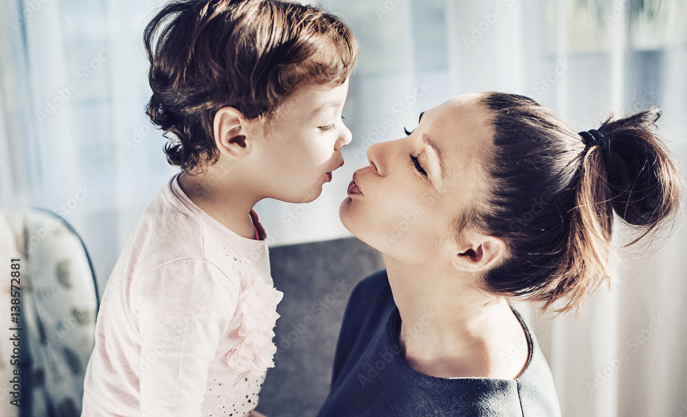 Naklejka premium Portrait of a mother kissing her beloved child