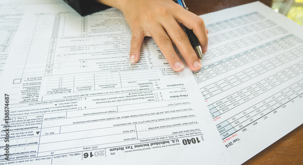 Obraz premium Business woman hand hold on the tax forms paper in business concept.