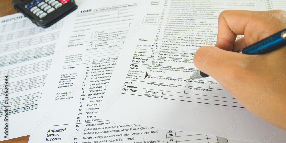 Obraz premium Hand hold pen on sign point on the tax forms paper in business concept