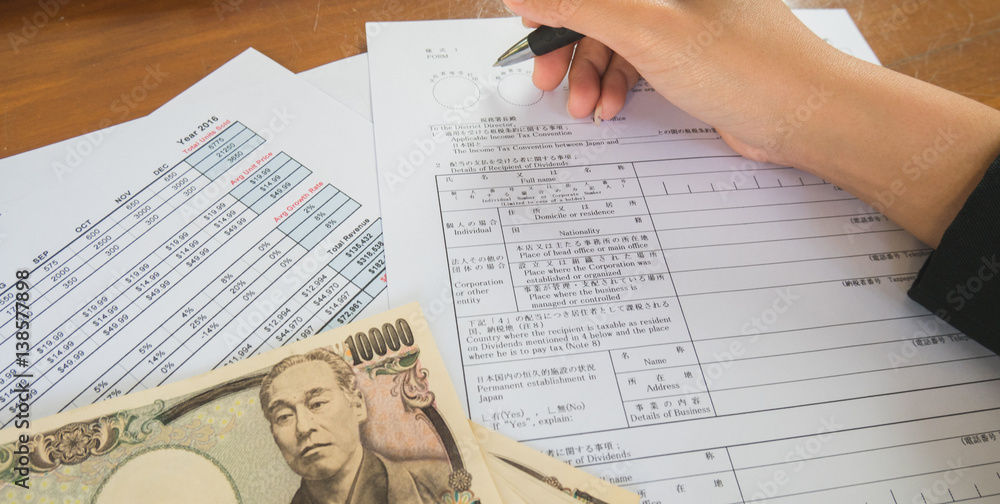 Woman hand hold pen fill in the details on the tax forms paper with yen moneyin business concept. Woman hand hold pen fill in the details on the tax forms paper with yen moneyin business concept.