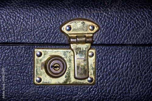 Lock golden color on an old suitcase made of black leather
