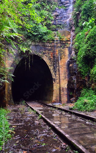 Waterfall cascading across the entrance to an historic abandoned railway tunnel in Helensburg  New South Wales  Australia