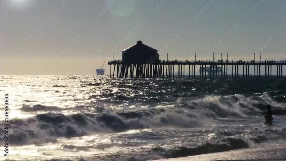 Pacific ocean with waves and a silhouette of a pier in the background on a sunny day in the afternoon. Pacific ocean with waves and a silhouette of a pier in the background on a sunny day in the afternoon.