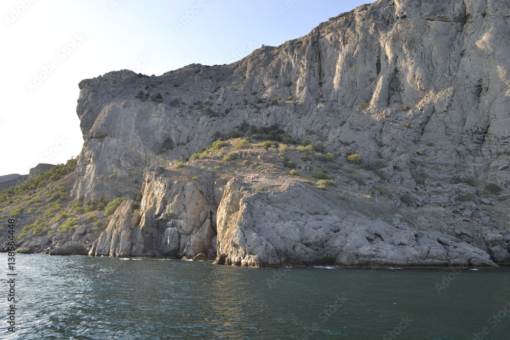 Fototapeta premium sea,beach,Crimea,Sudak,fortress,castle,Genoese fortress,Ukraine,mountains,cliffs,rocks, sea,sky,blue sky,sun,sea, stones,waves,spray,water,cat,gray cat,cat,smoothie,drink,glass,cherry,cocktail,Seagull
