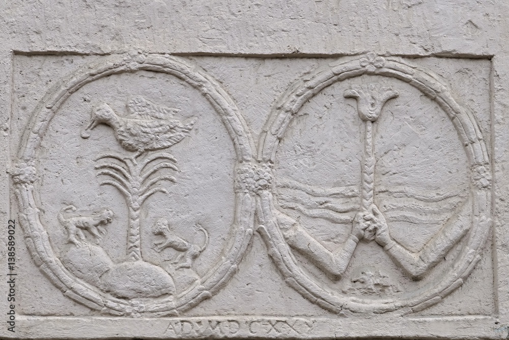 Two round anaglyphs with palm, duck, monkeys and two hands holding a flower on wall of neobaroque-classicistic mansion in Horne Lefantovce, Slovakia