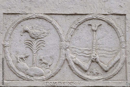 Two round anaglyphs with palm, duck, monkeys and two hands holding a flower on wall of neobaroque-classicistic mansion in Horne Lefantovce, Slovakia photo