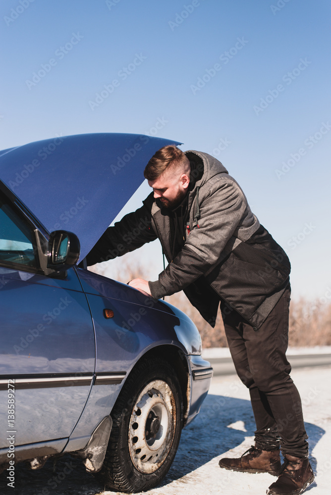 man repairing a car standing at the hood