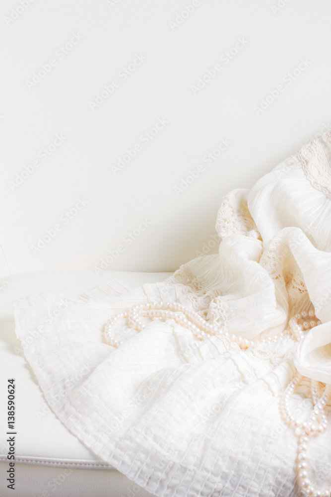 Female accessories - dress and jewellery on white chair still life Female accessories - dress and jewellery on white chair still life